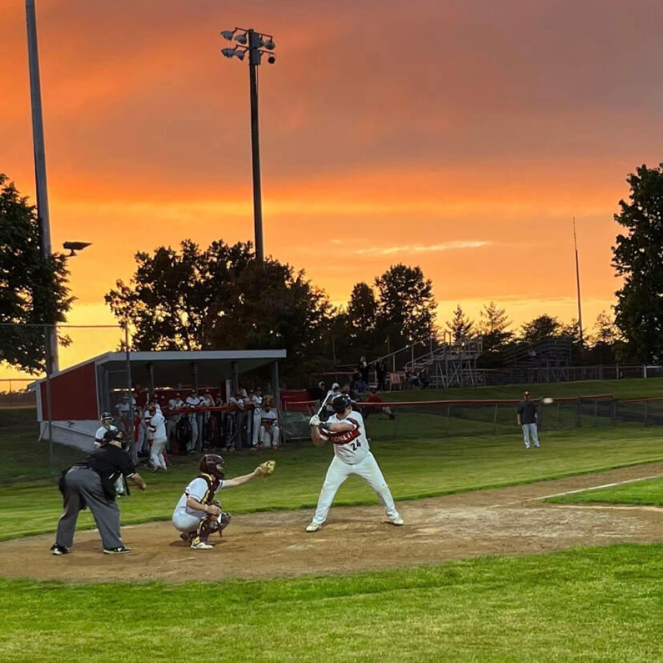 Cardinal Community School District baseball player up to bat at sunset.