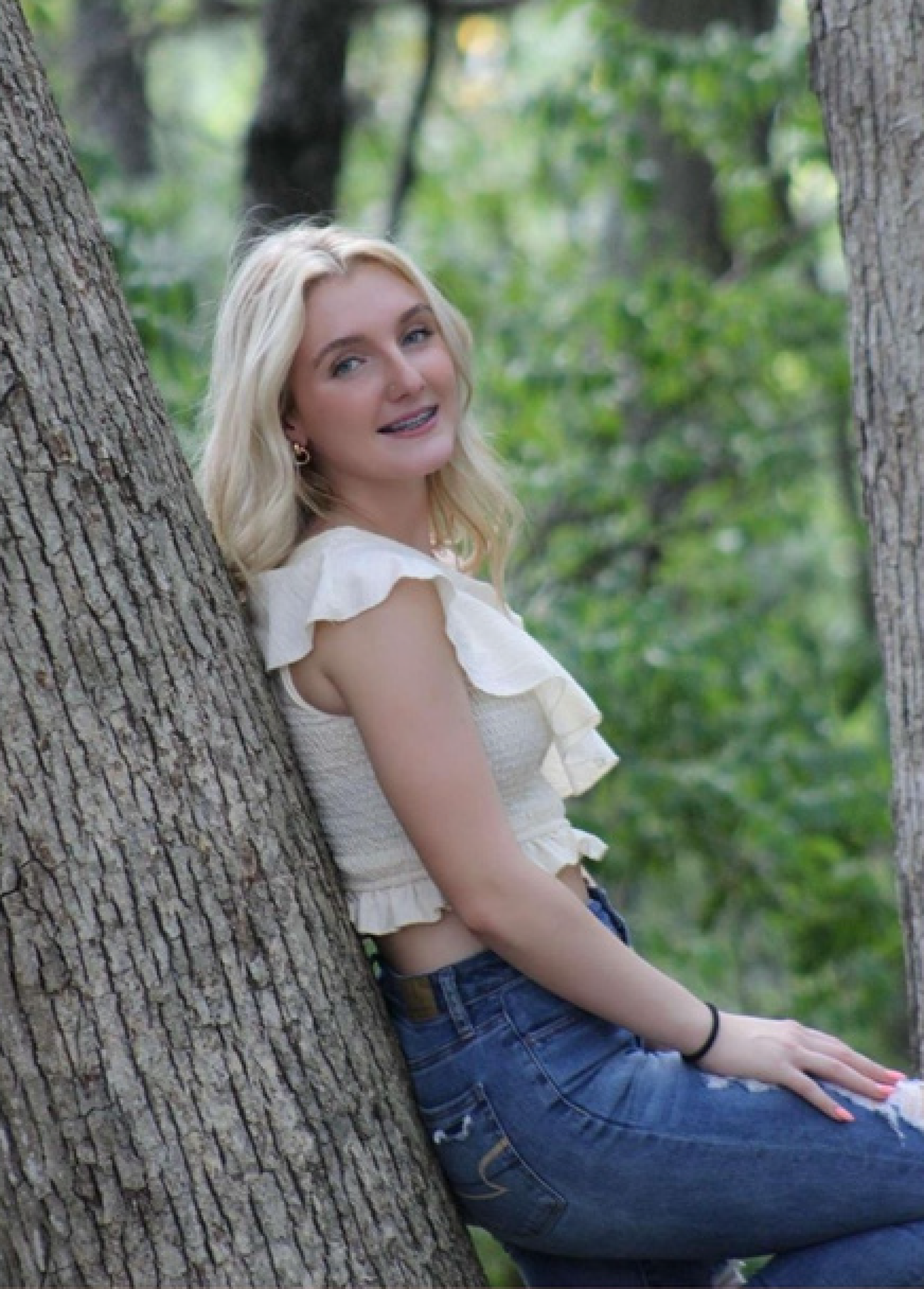 female student posing on a tree trunk