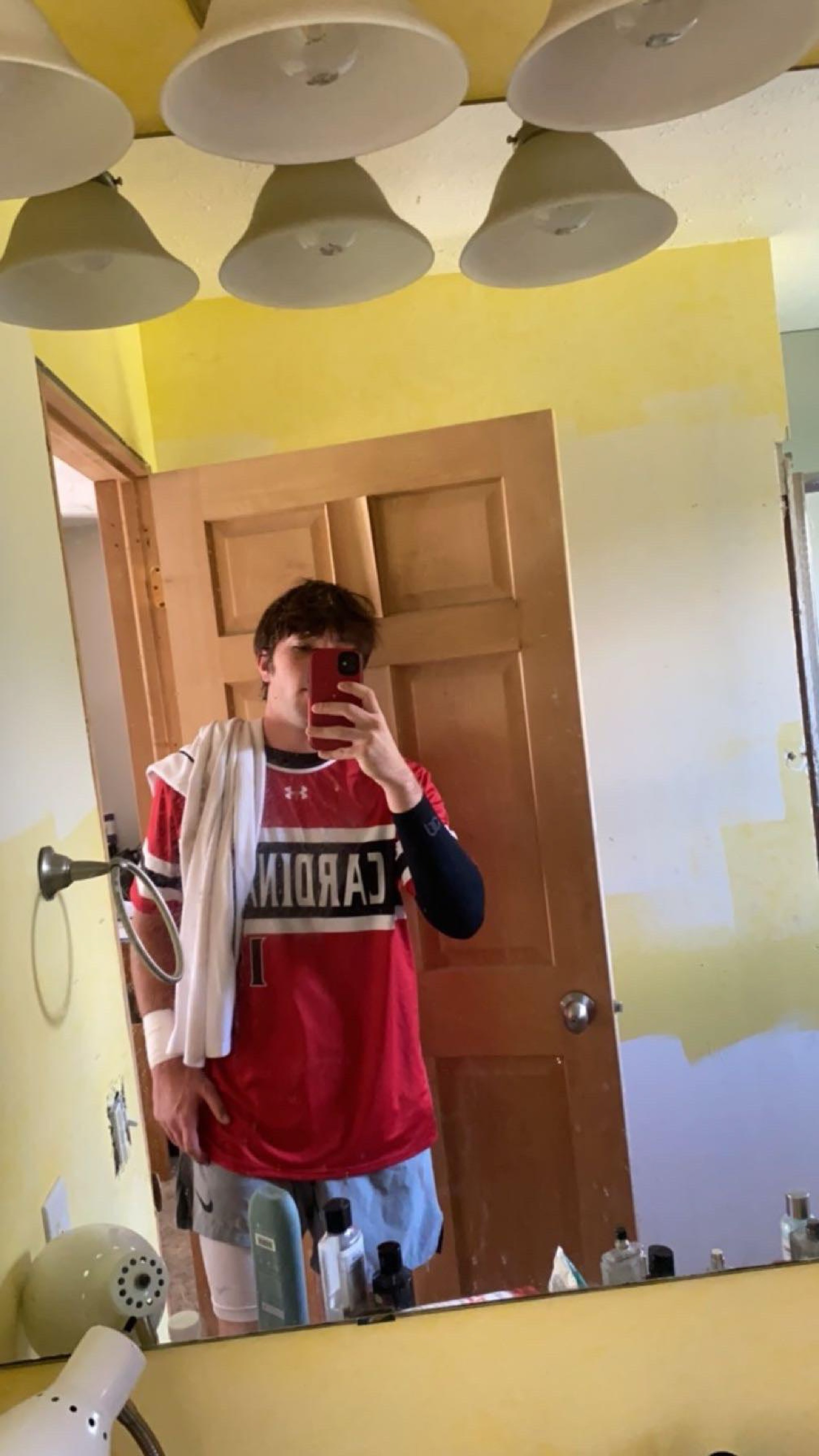 Male dressed in basketball uniform taking selfie in mirror