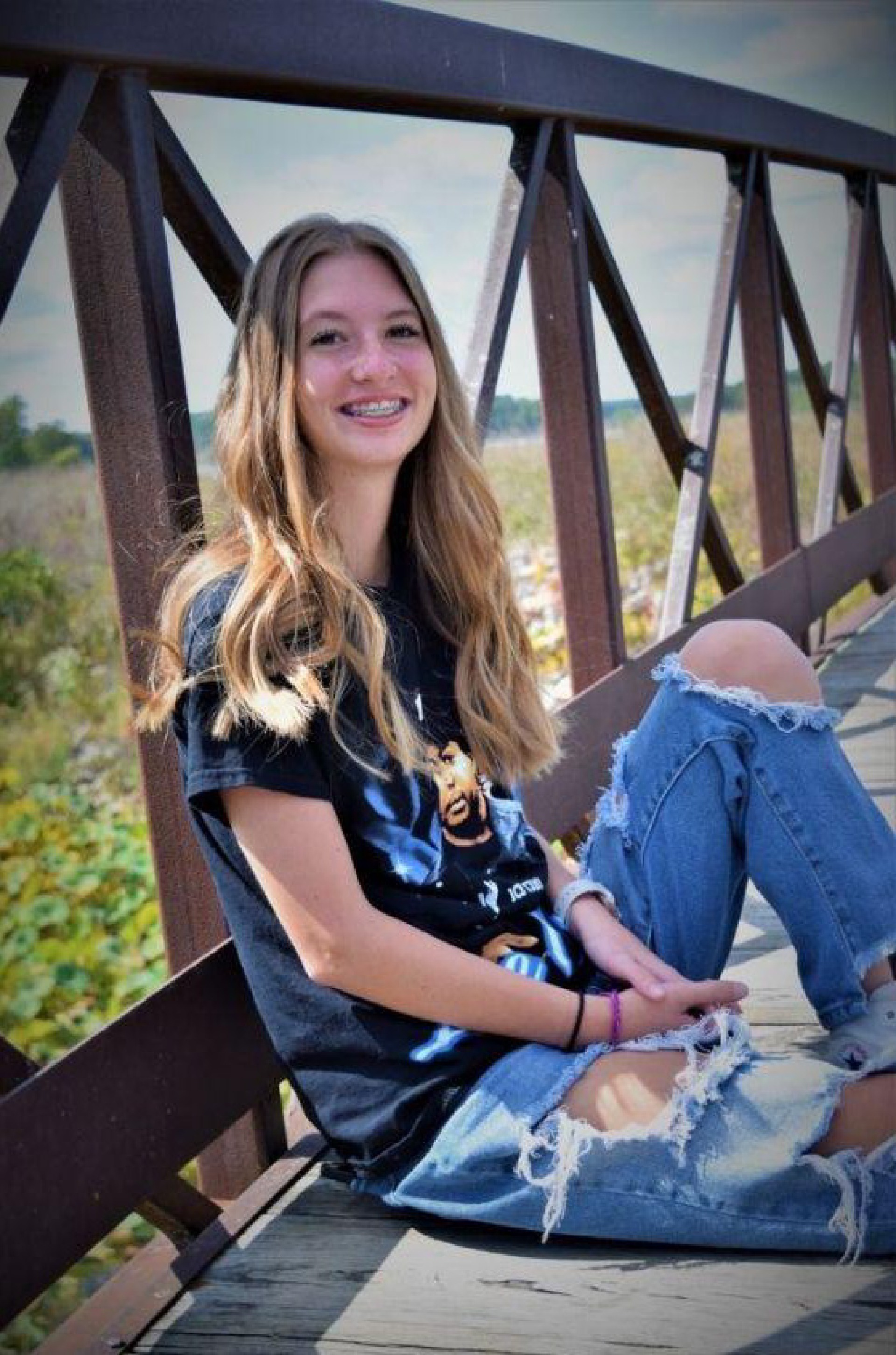 Female posing while sitting on a walking bridge