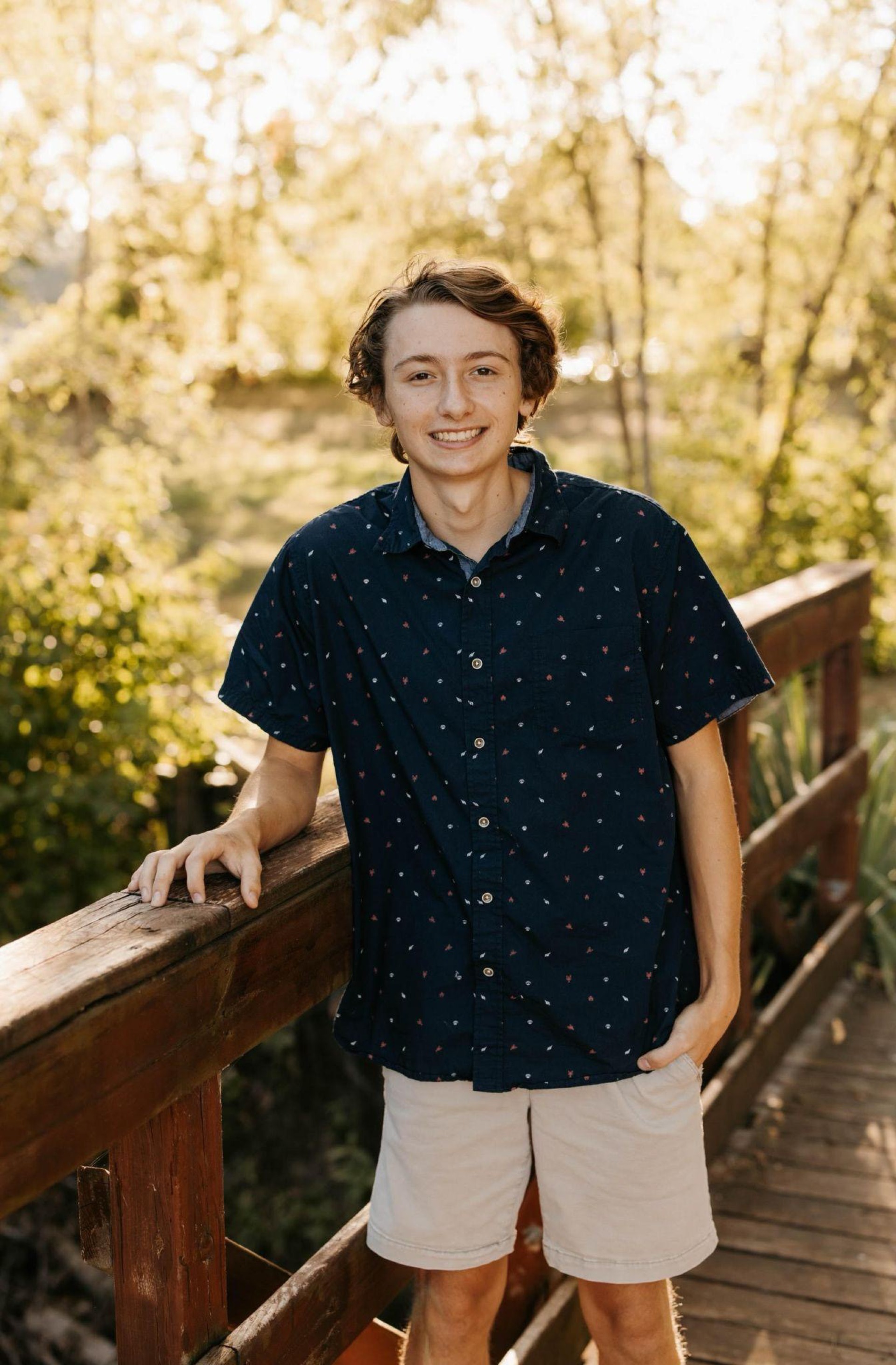 Male student posing on a nature trail bridge