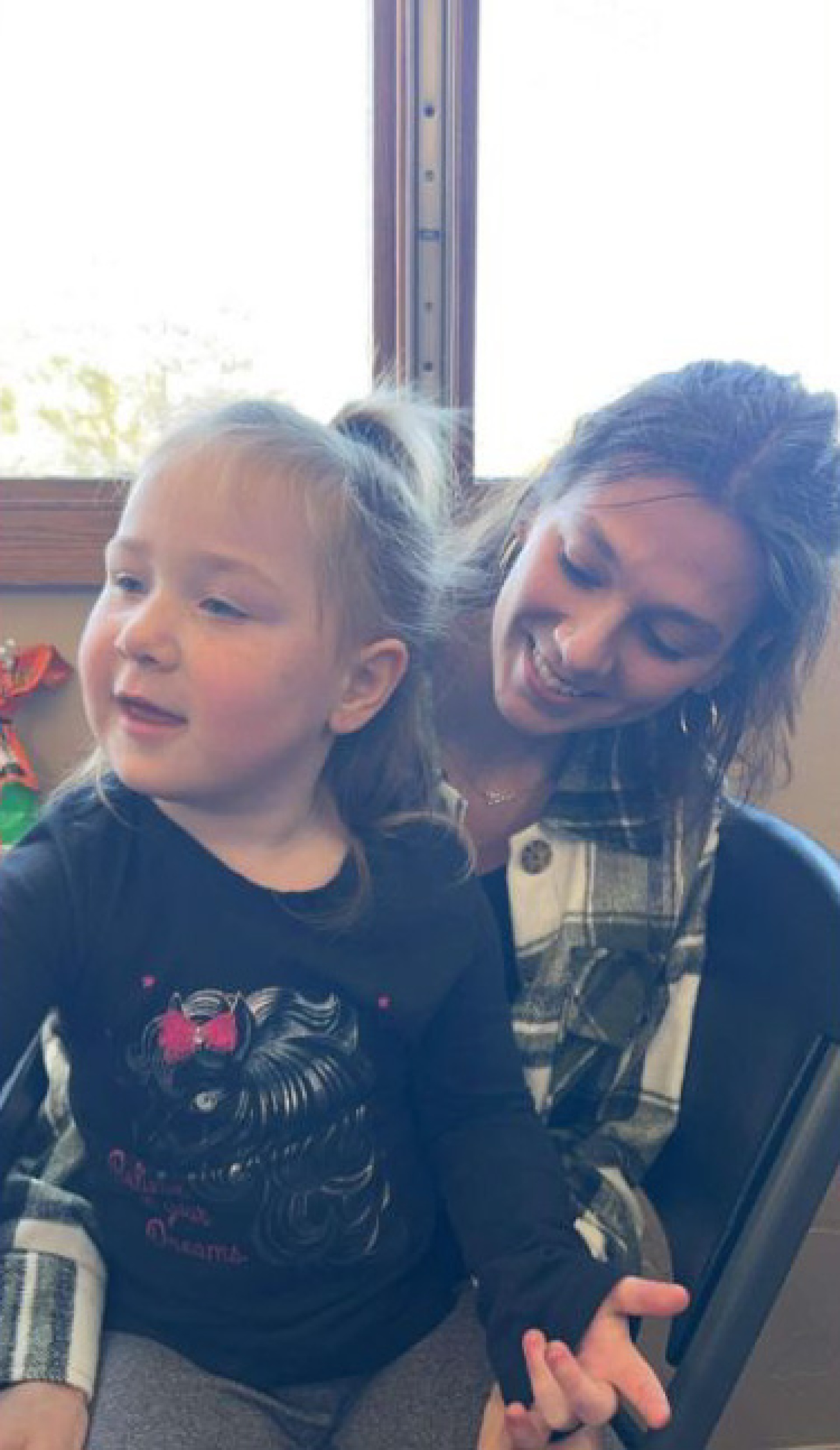 Teenage female with young girl sitting on lap