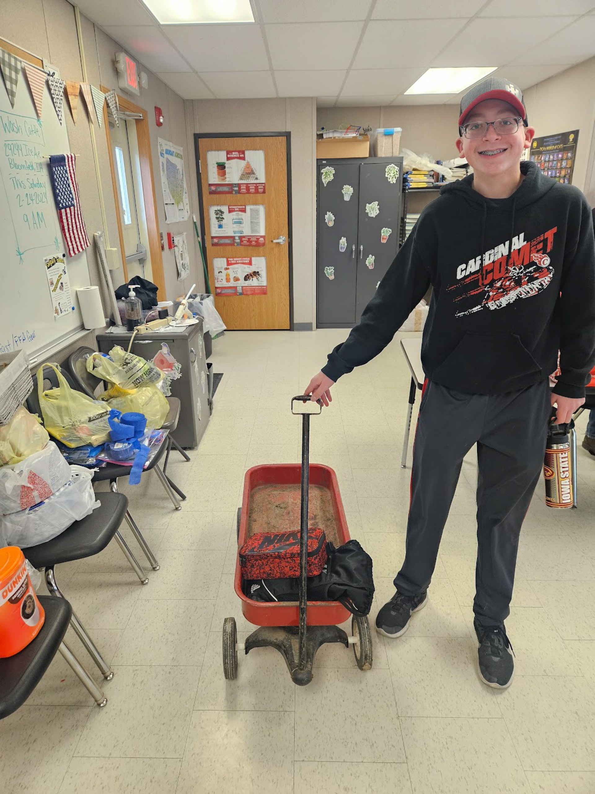 Male student posing next to small red wagon.